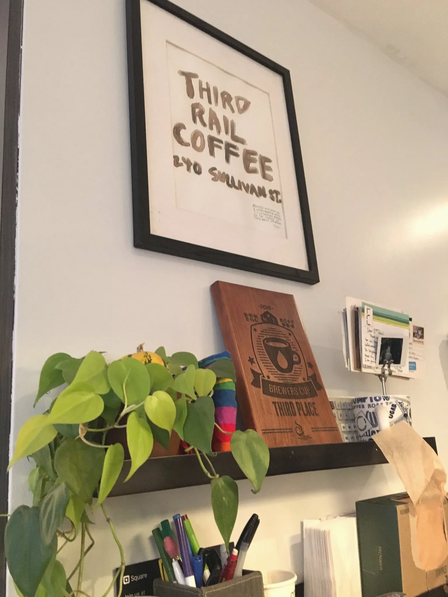 A café wall sign beside shelves and plants